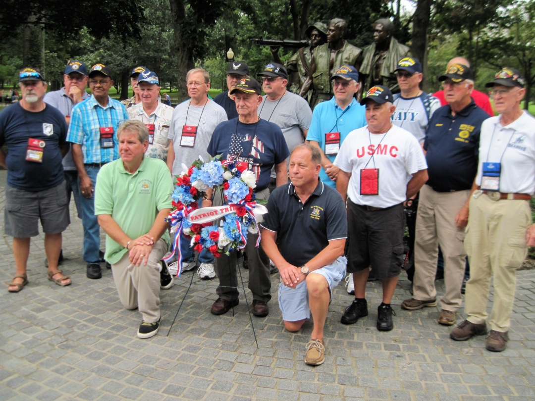Assemblyman Steve Hawley [right of wreath] poses for a photo with Assemblyman Michael DenDekker [left of wreath] and veterans in front of the Vietnam War Memorial during last year’s Patriot Trip to Washington D.C.