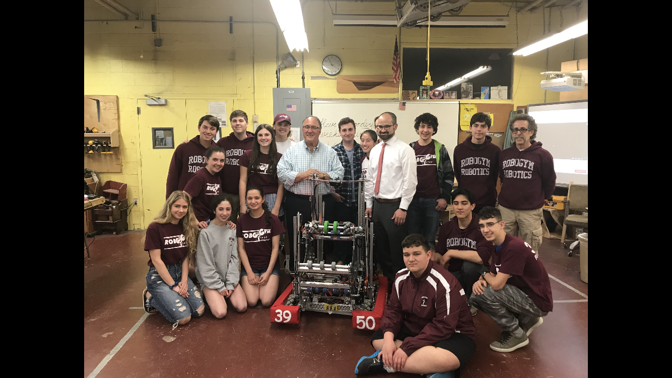 Assemblyman Montesano, Assemblyman Ra and North Shore High School Robotics Team Supervisor Stephen Peroni pose with team members and their creation, “Fran”.